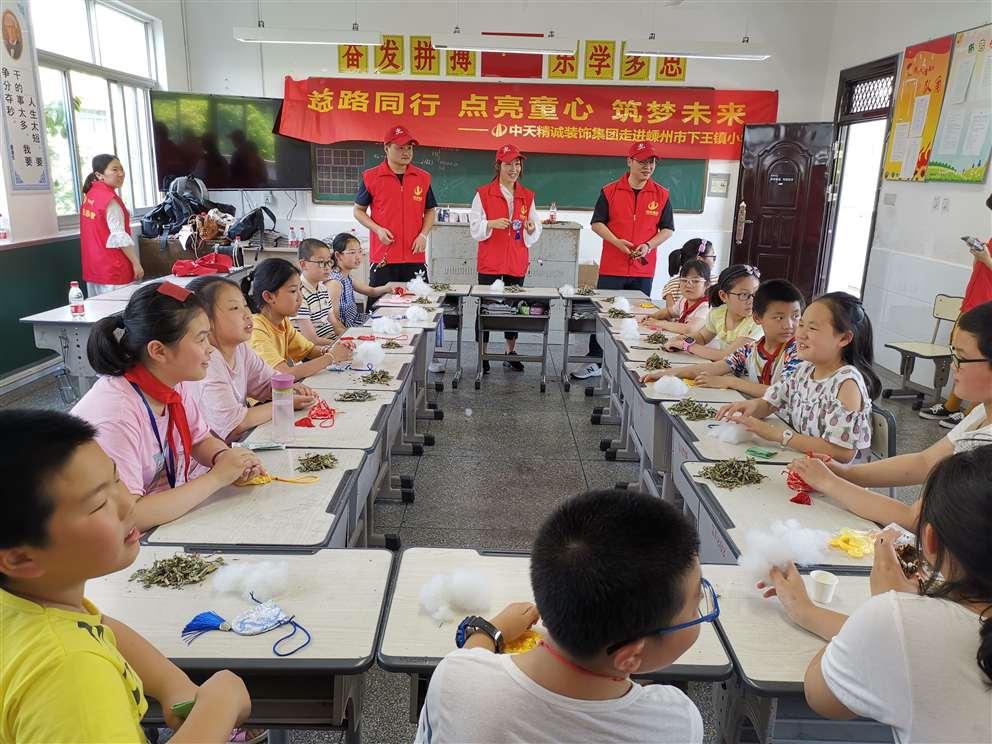 6月5日，中天精誠裝飾集團的志愿者們在總經理助理施江鋒的帶領下來到嵊州市下王鎮中心小學，為鄉村小學的孩子們帶去精彩的職業體驗項目、端午禮物及溫暖的陪伴。  此次DO益行為孩子們帶來了飲品研發師、禁毒警察、美發設計師、魔術師、時裝設計師、郵遞員、印染師、百貨員的體驗項目。活動現場，兩個多小時的體驗，排隊等候、好奇、嘗試、探索與實踐，打破了志愿者與孩子們之間的陌生感，也圓了孩子們的職業夢。   臨近端午節，中天精誠裝飾的志愿者們還帶來了一項特色傳統文化活動——制作端午香囊， 佩香囊，是端午傳統習俗之一，香囊內通常填充一些具有芳香開竅的中草藥，有清香、驅蟲、避瘟、防病等功能。這份“體驗感十足”的端午節禮物贏得學生們的喜愛，在體驗課上，學生們了解端午節的由來和習俗并親手制作端午香囊，把關心裝入香囊送給家人。  “人人可慈善、人人應慈善”，付出、愛、公益、夢想，這些關鍵詞串起了志愿者與鄉村孩子的心，我們會一起努力，在成長的路上學會勇敢面對各種挑戰，最終實現自己的夢想。
